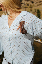Close view of the blue polka dot pajama collar and brown bow on the chest pocket.