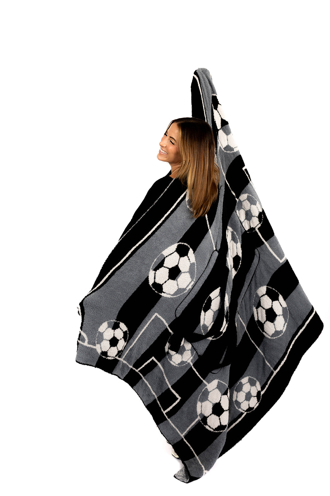 Woman wearing a black and gray patterned blanket with soccer ball design on a white background