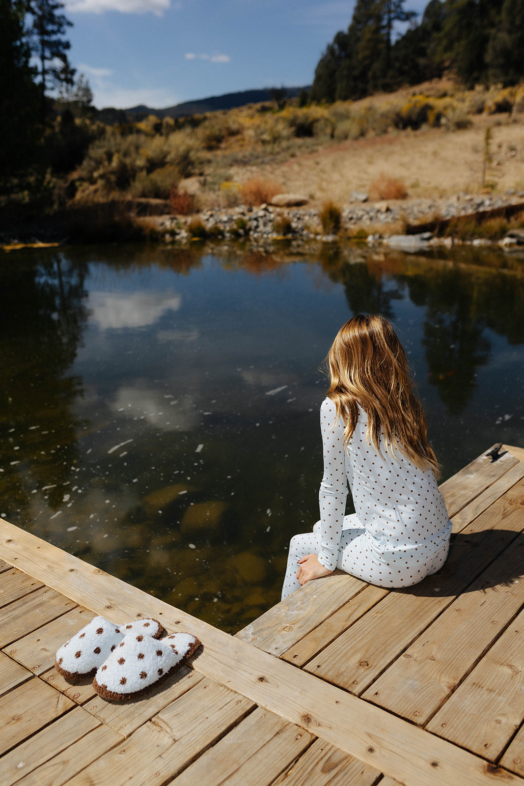 Back view of a child seated in the blue and brown polka dot pajama set.