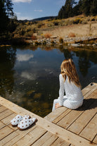 Back view of a child seated in the blue and brown polka dot pajama set.