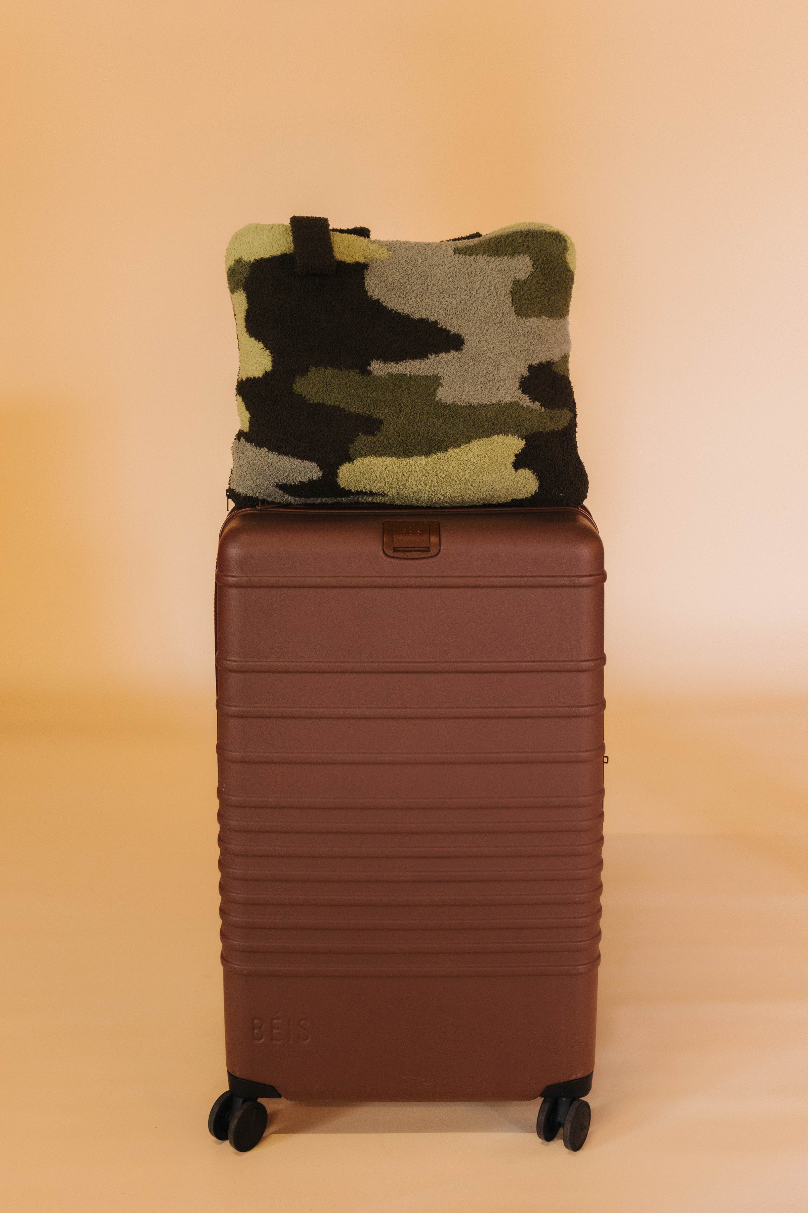 camo quillow on brown suitcase