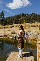 Full length front view of the brown fluffy polka dot robe tied at the waist on a dock.