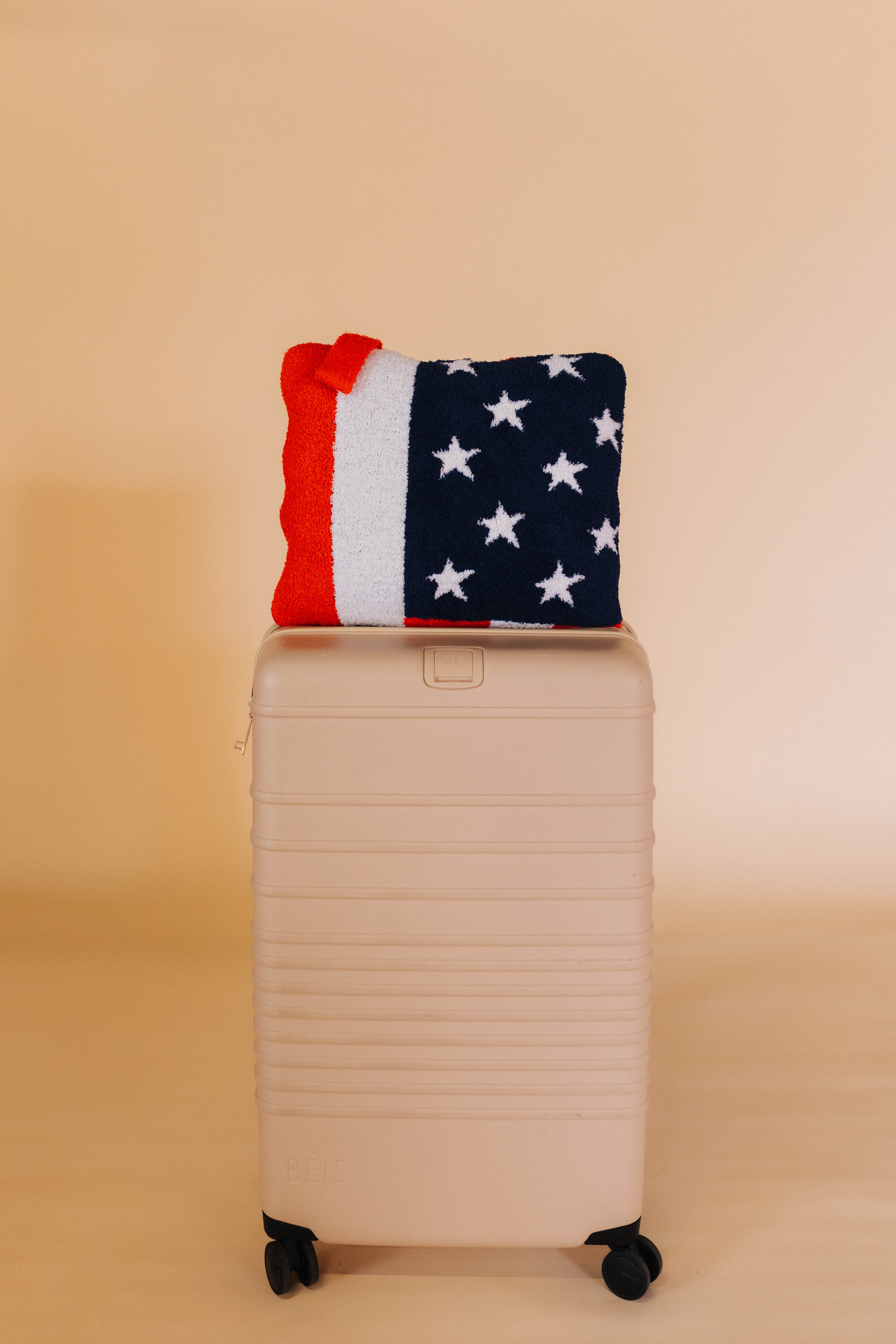 american flag quillow on top of tan suitcase