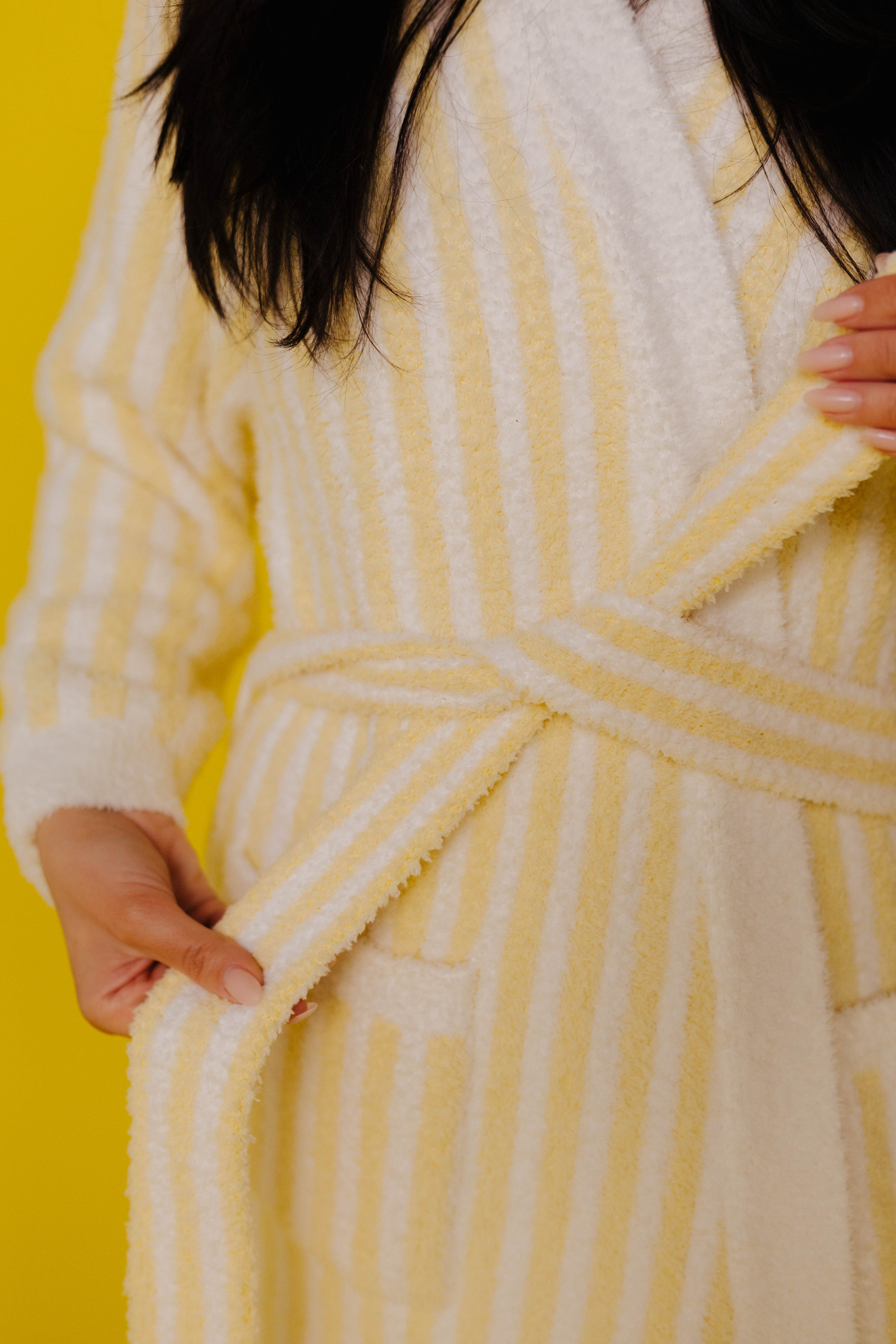 Person wearing a yellow and white striped robe against a yellow background