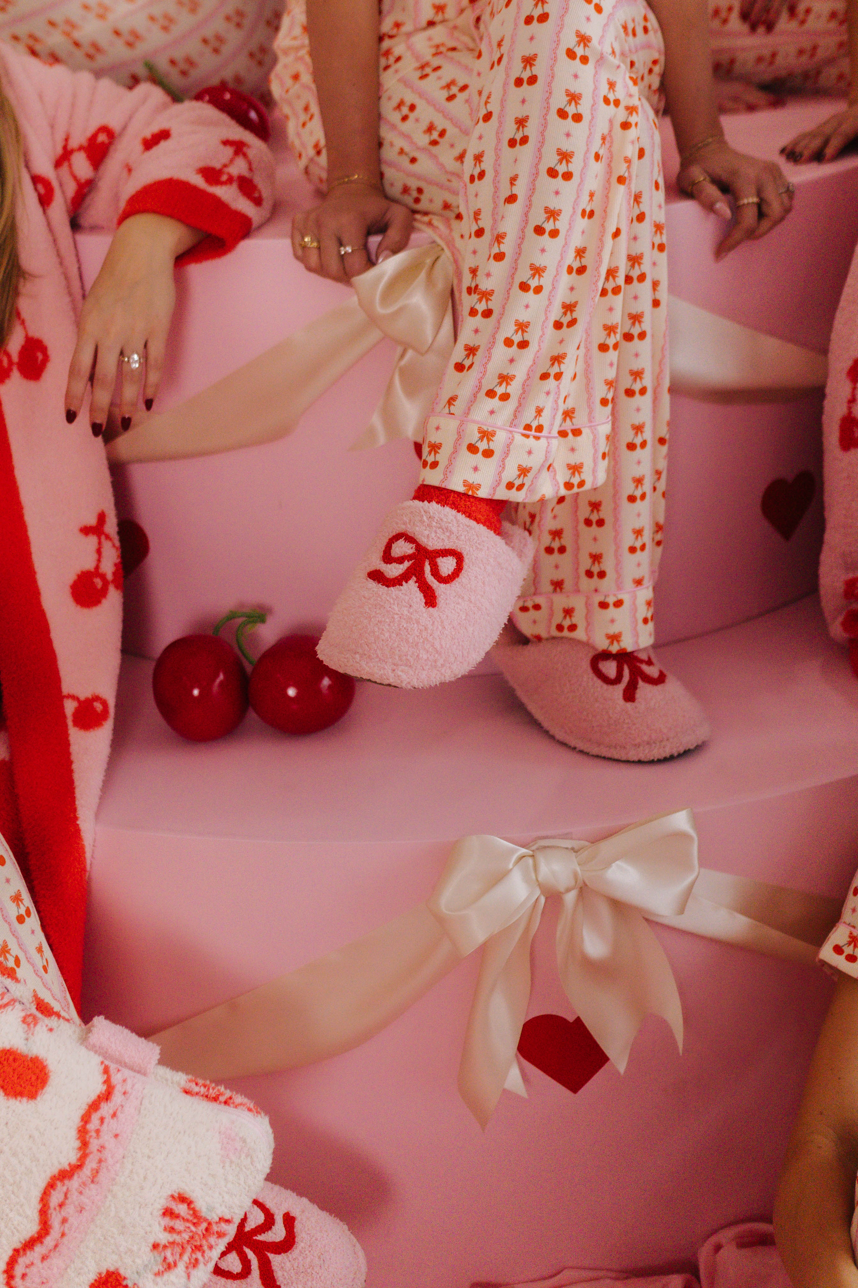 Person wearing a cherry-themed outfit with matching slippers on a pink chair.