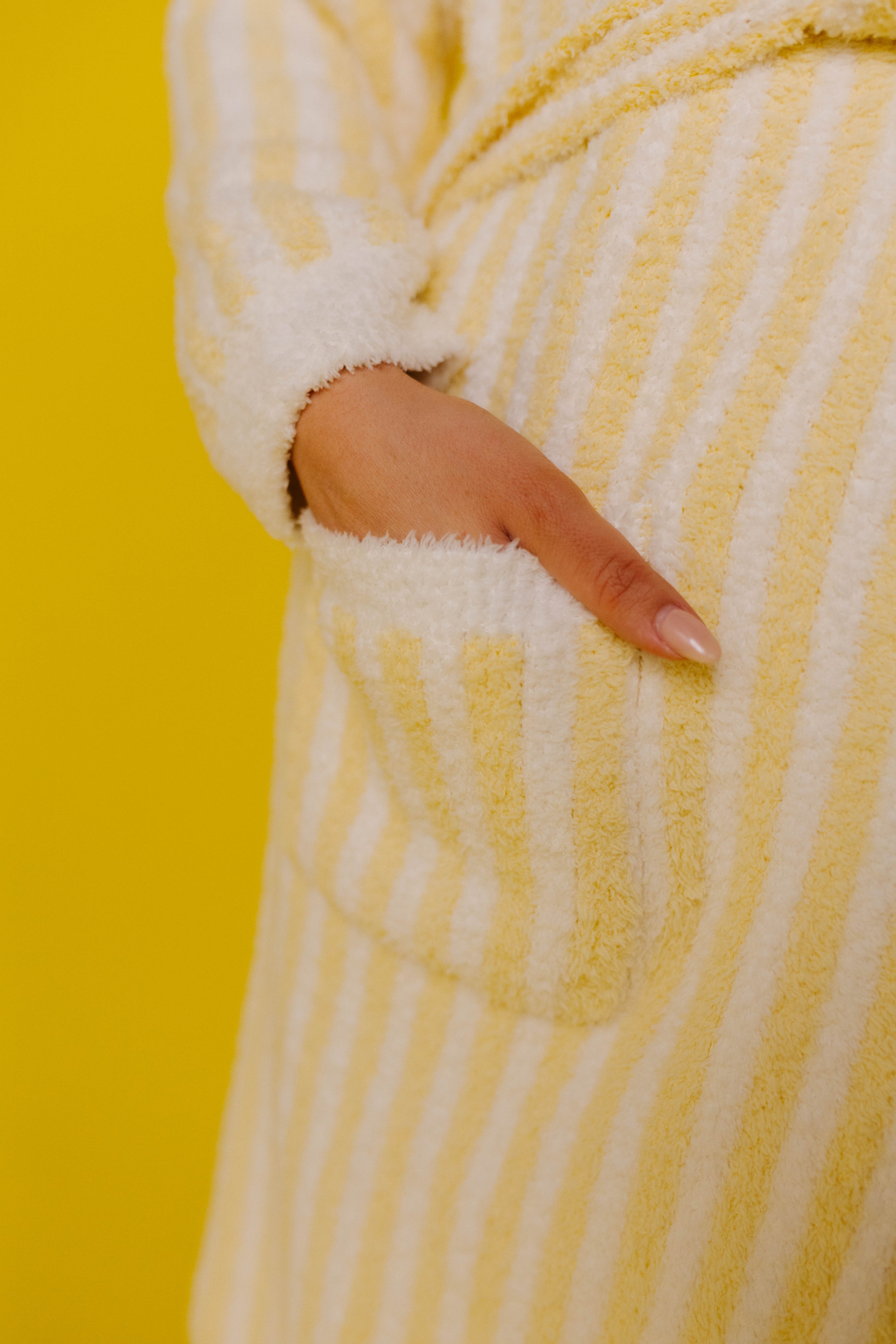 Close-up of a yellow and white striped robe with a pocket on a yellow background