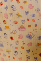 Patterned fabric with food and kitchen-themed illustrations on a butter yellow background