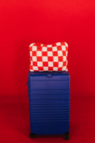 red check quillow on top of a blue suitcase in front of a red background