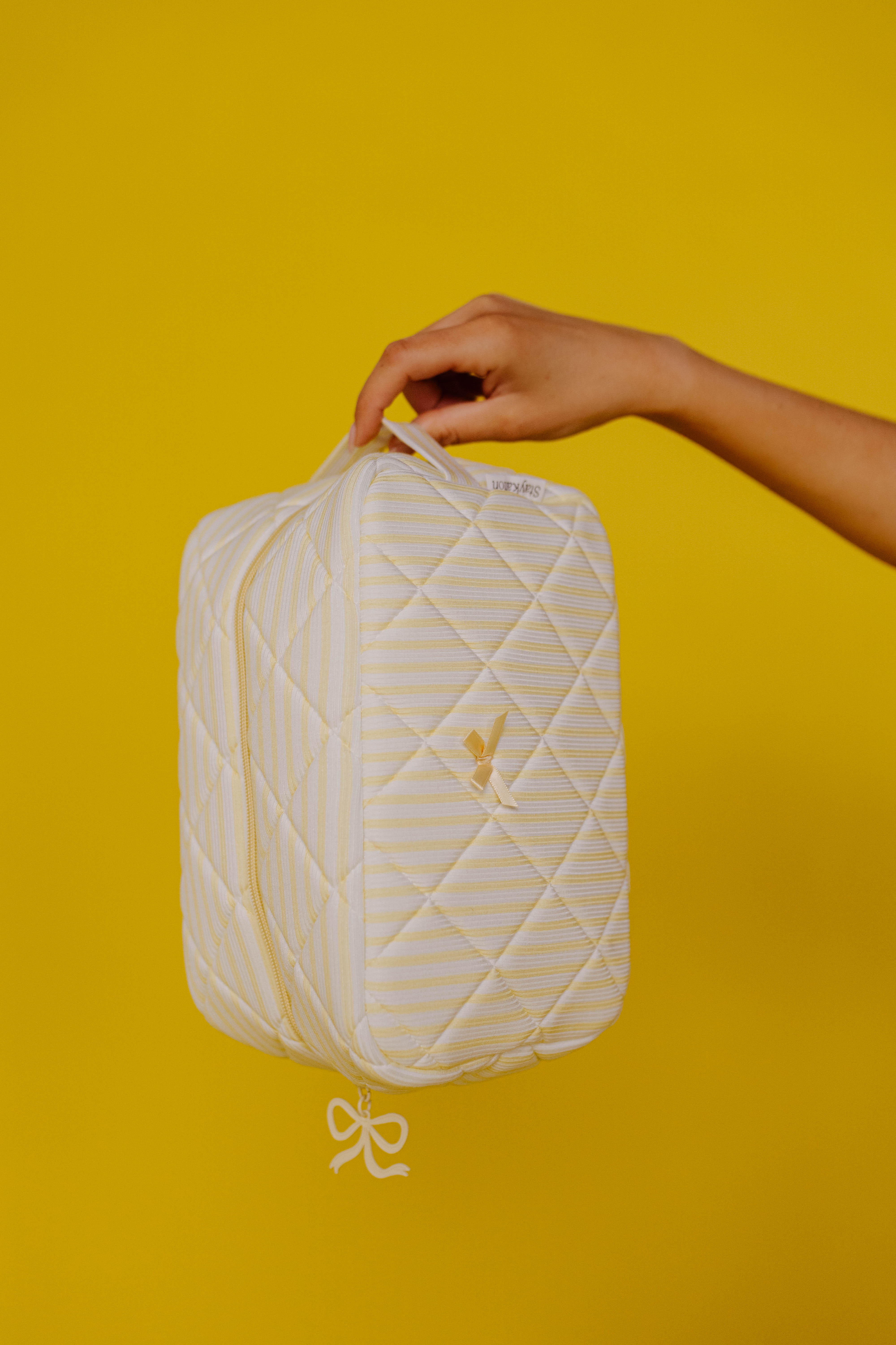 holding up the cosmetic bag on a plain yellow background