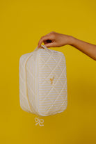 holding up the cosmetic bag on a plain yellow background