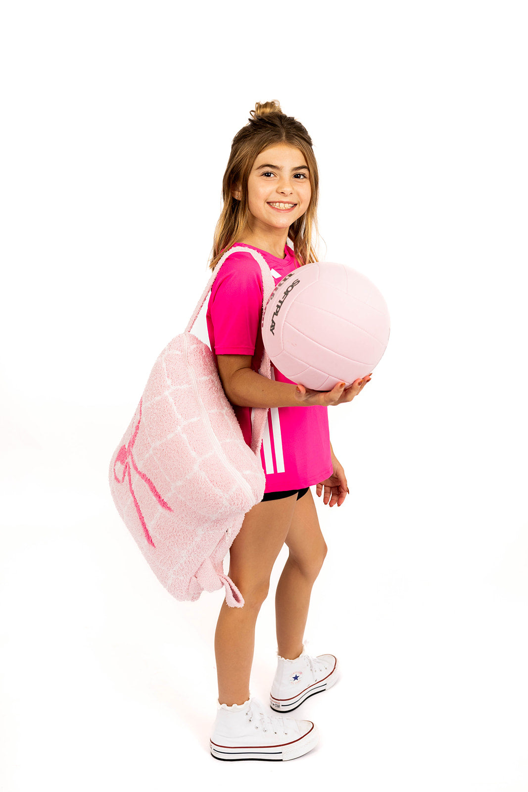 Young girl holding a pink volleyball quillow and volleyball on a white background