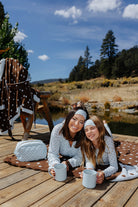 Adult and child wearing matching blue and brown polka dot pajamas, smiling on a dock.