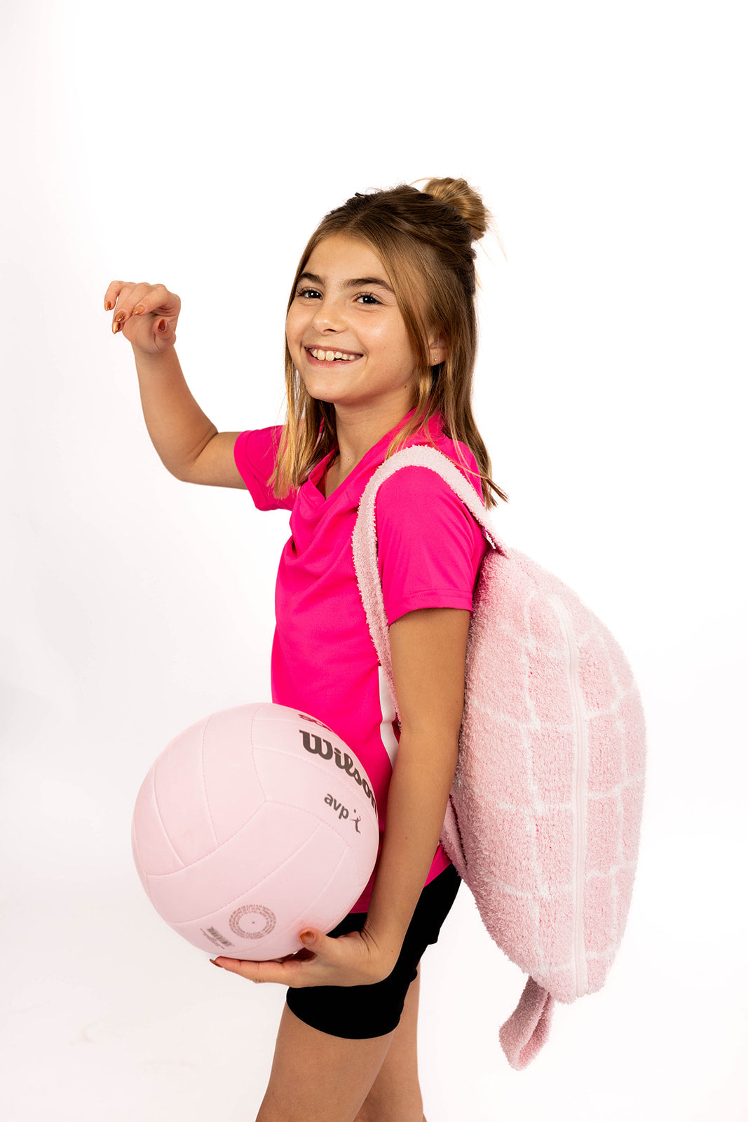 Young girl in pink shirt with pink volleyball and pink quillow on white background