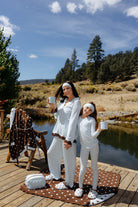 Child wearing light blue and brown polka dot pajamas beside a matching adult outfit.