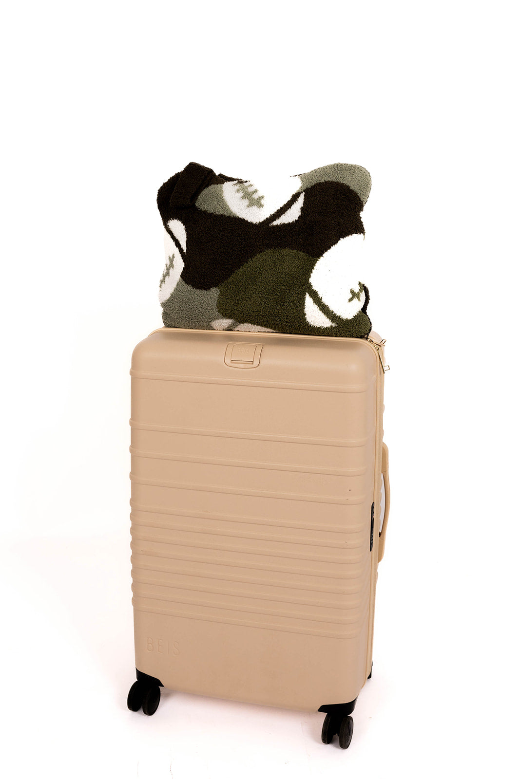 Beige suitcase with a camo football patterned quillow on a white background