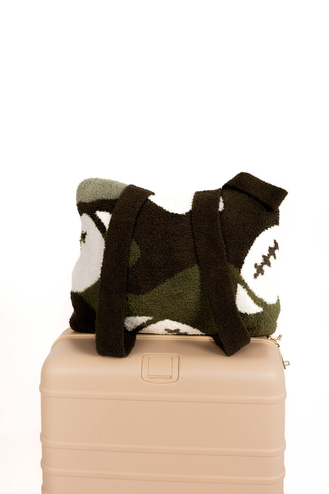 Camo patterned football quillow sitting on top of a beige suitcase