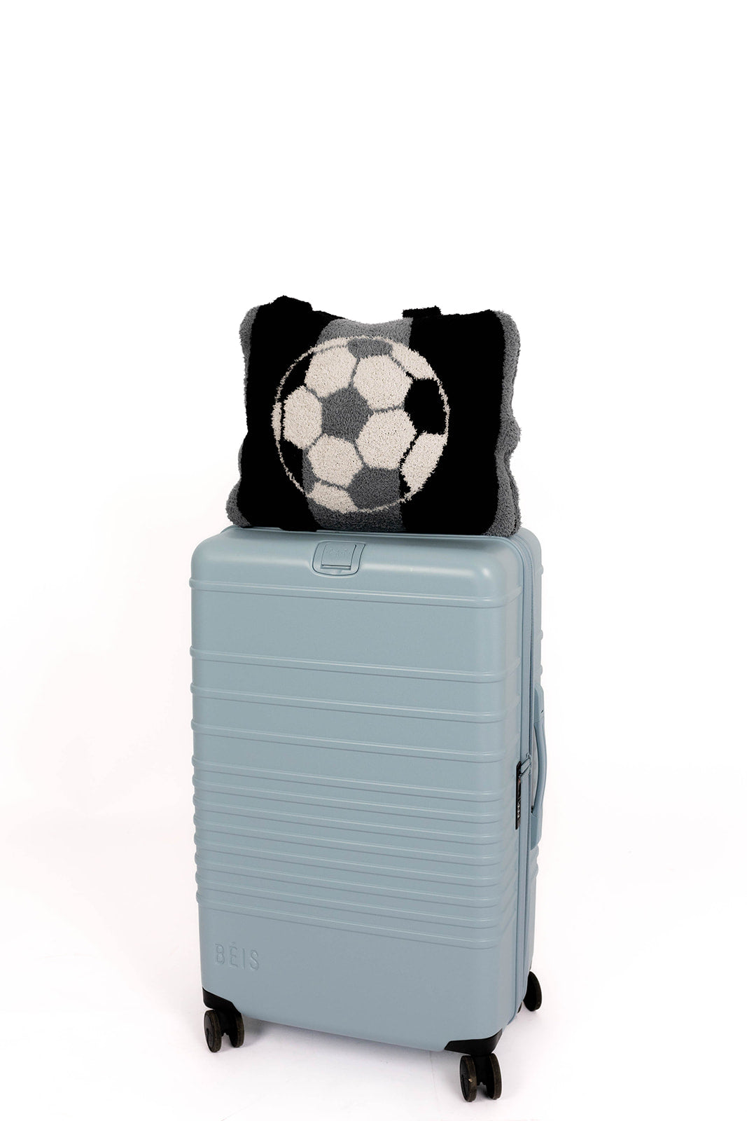 Light blue suitcase with a black and white patterned soccer quillow on a white background
