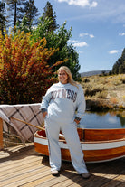 Full length front view of a model wearing the light blue Hot Mess sweatshirt and plaid stripe sweatpants on a dock.