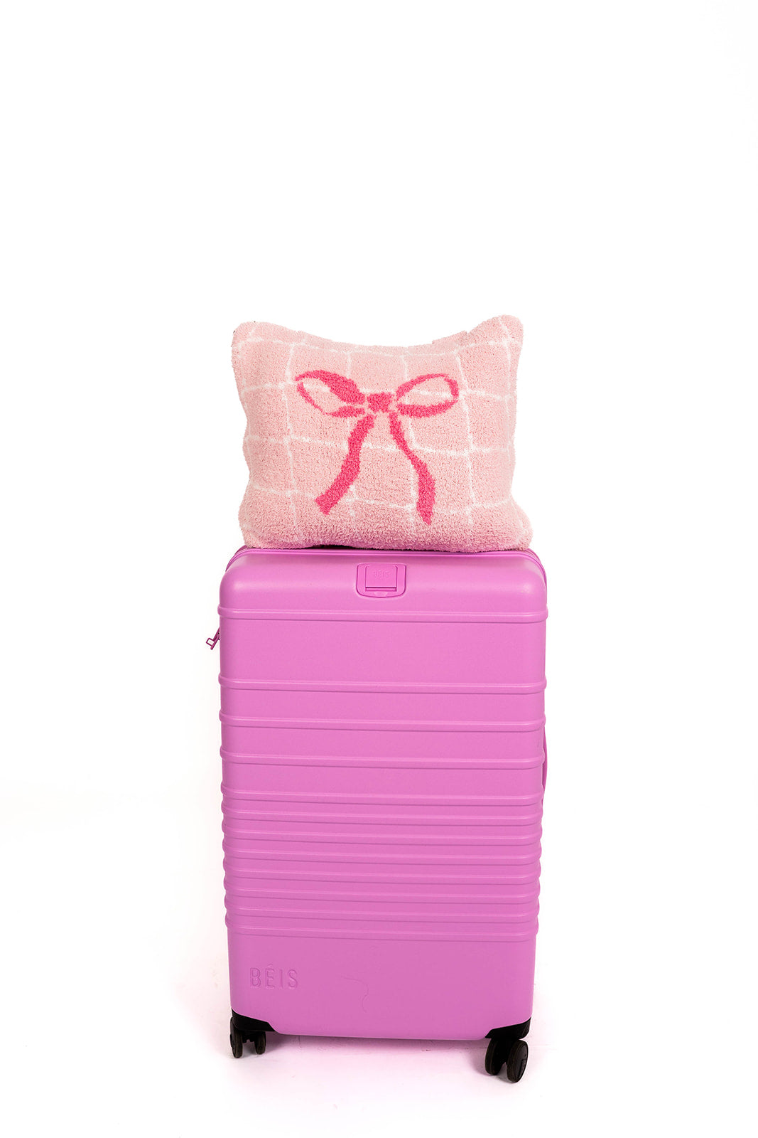 Pink suitcase with a quillow featuring a bow on a white background