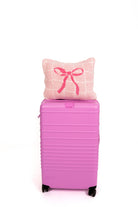 Pink suitcase with a quillow featuring a bow on a white background