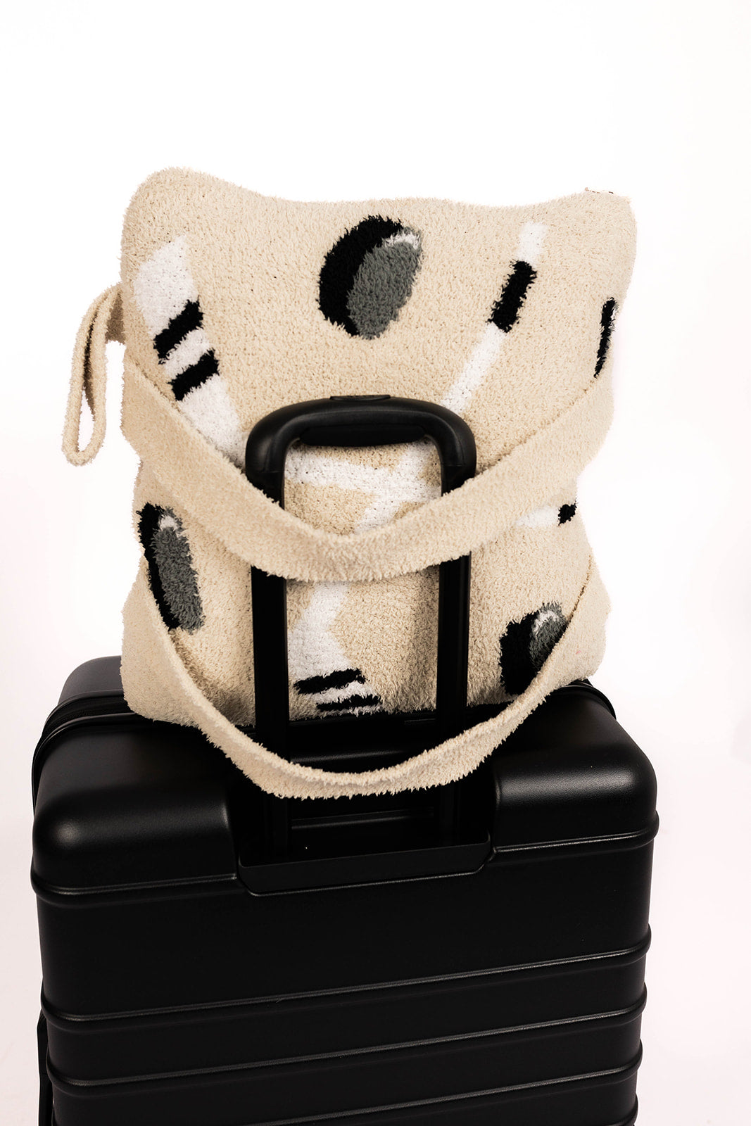 Beige hockey quillow sitting on a black suitcase