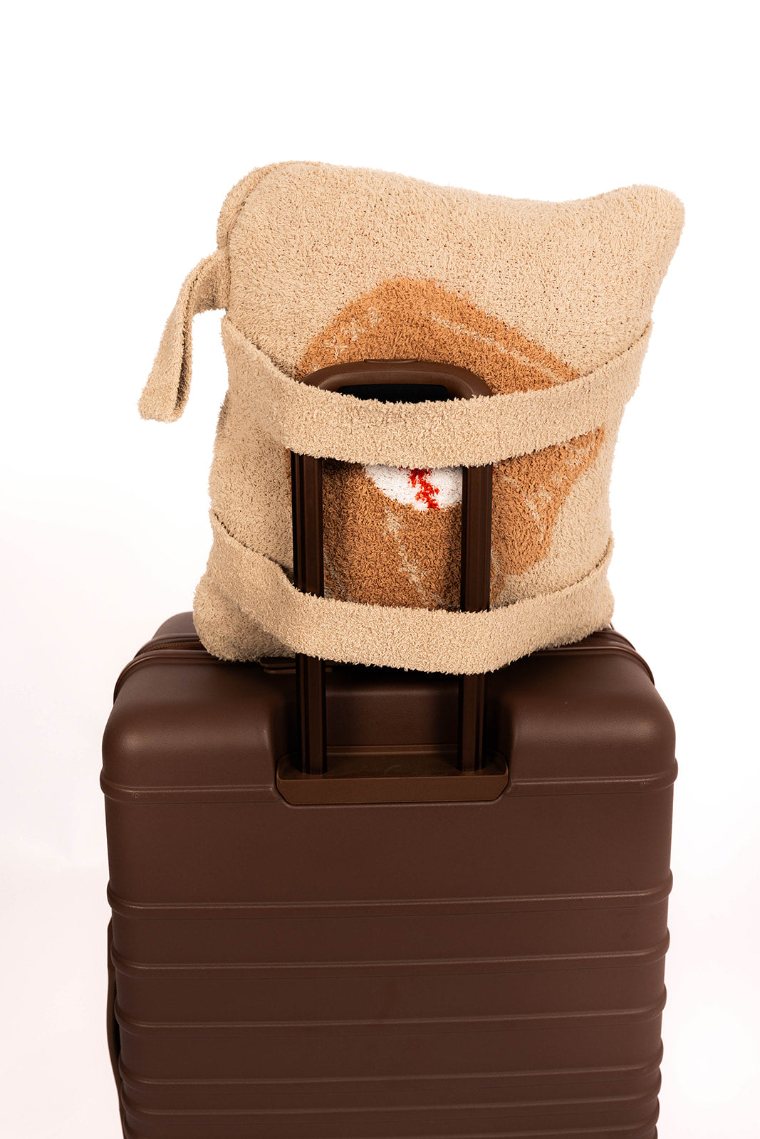 Beige quillow with straps on top of a brown suitcase