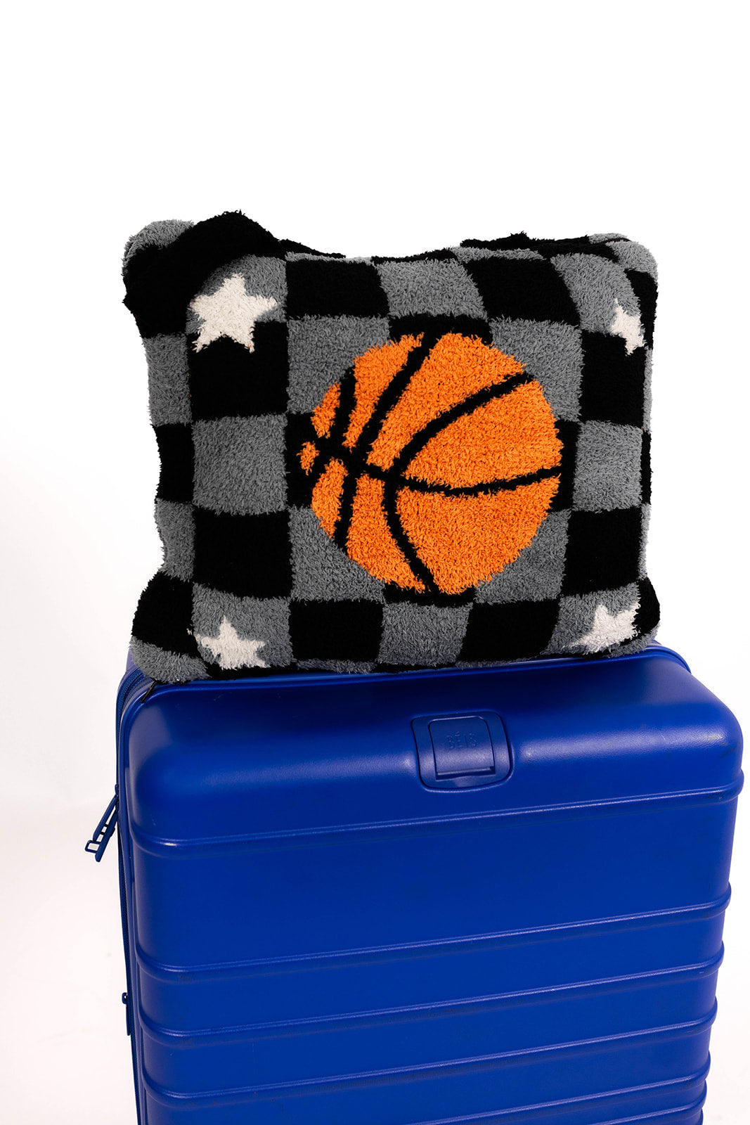 Checkered quillow with a basketball design on top of a blue suitcase