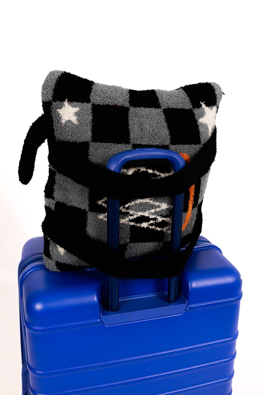 Checkered basketball quillow on a blue suitcase with a white background