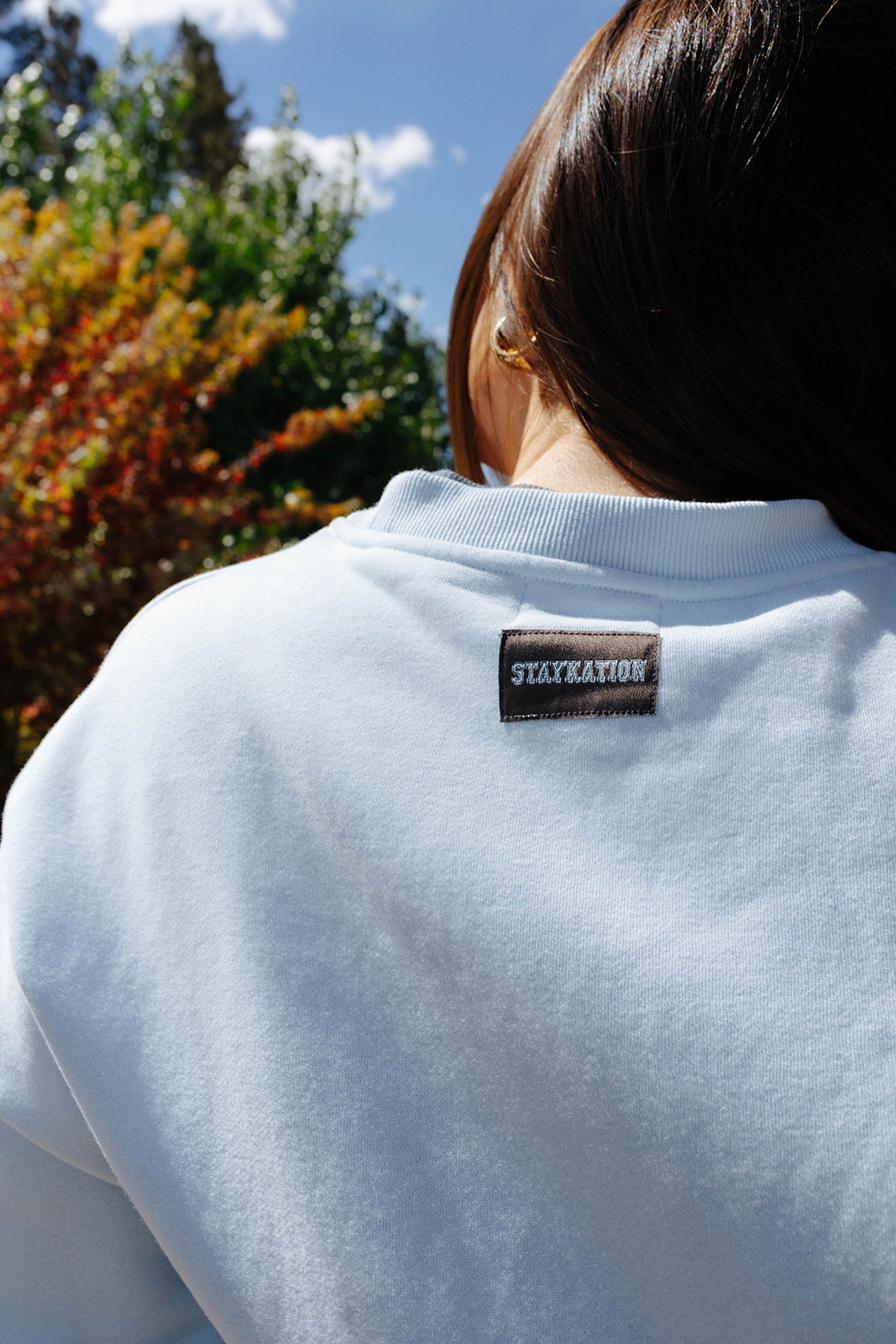 Back neckline and Staykation label on the light blue sweatshirt.