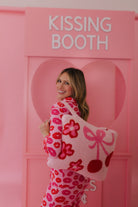 Woman in a pink and red outfit standing in front of a 'Kissing Booth' sign. showing the quillow on her back. 