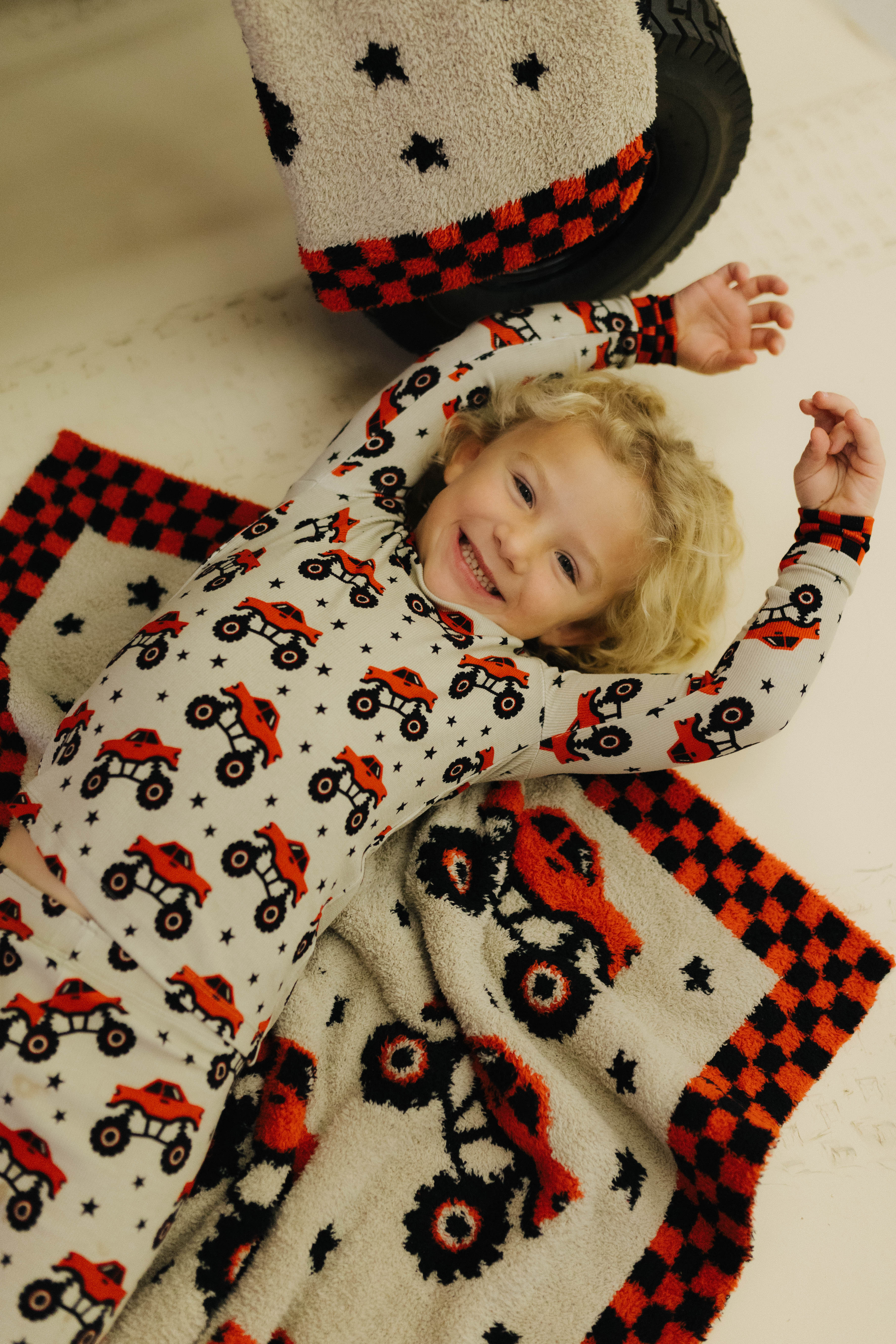 Child wearing a onesie with red and black patterns laying on the blanket
