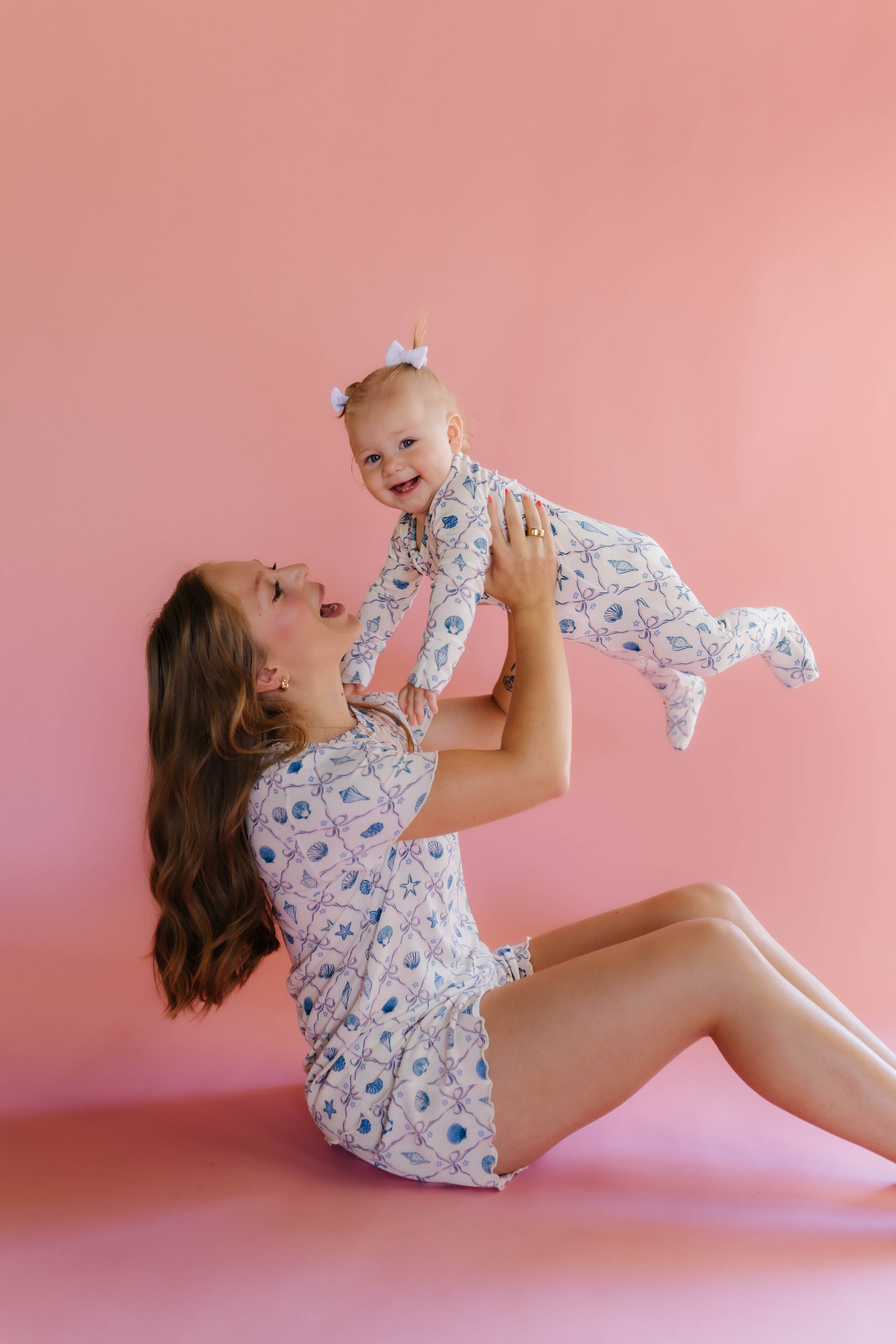 Woman and baby in matching pjs against a pink background