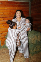 Adult with two children wearing matching brown stripe pajamas in a stable.