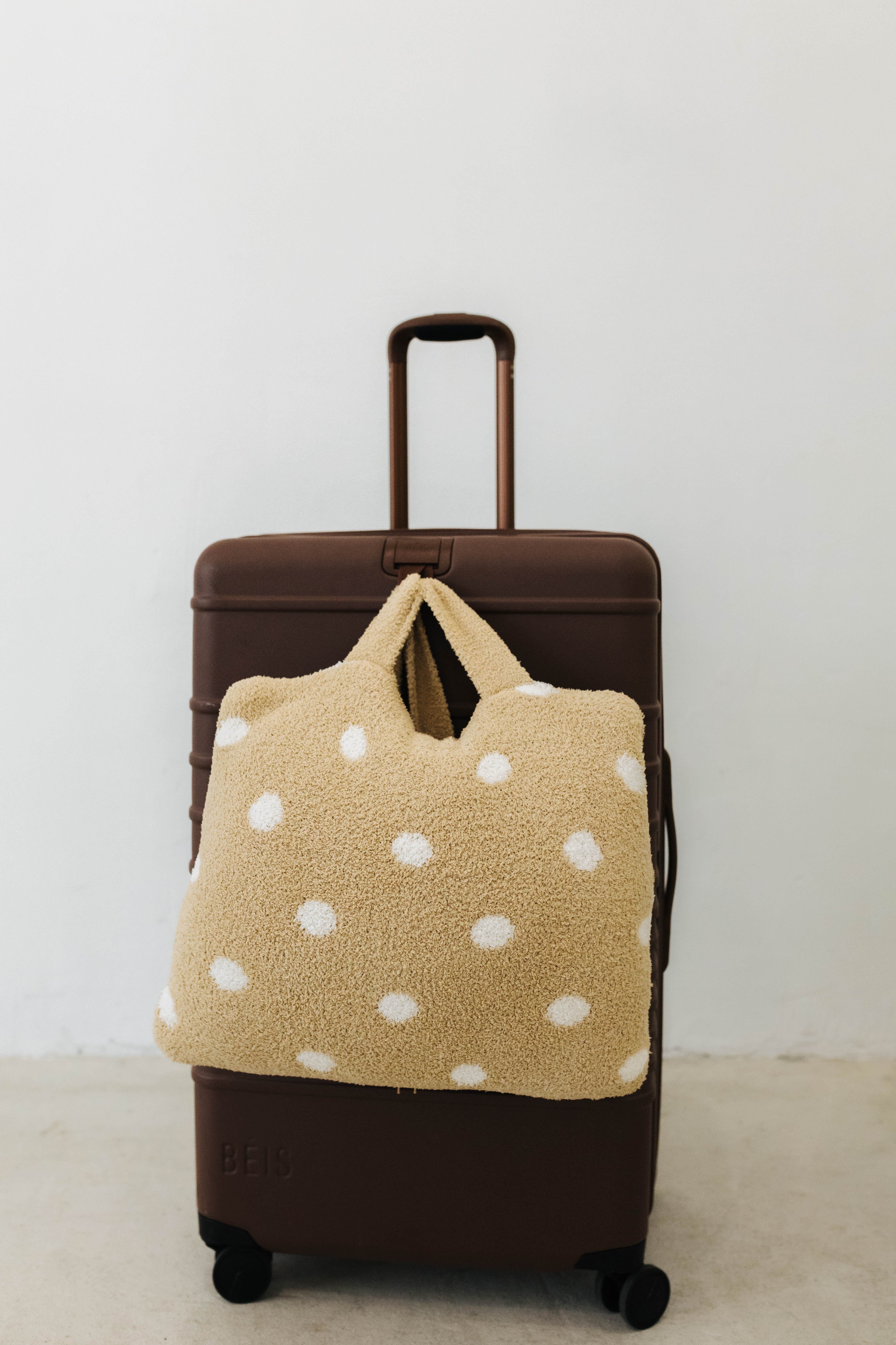 polka dot quillow on brown suitcase