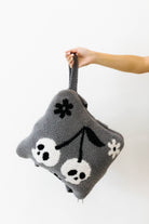 holding skelly backpack and wristlet quillow by the wrist 