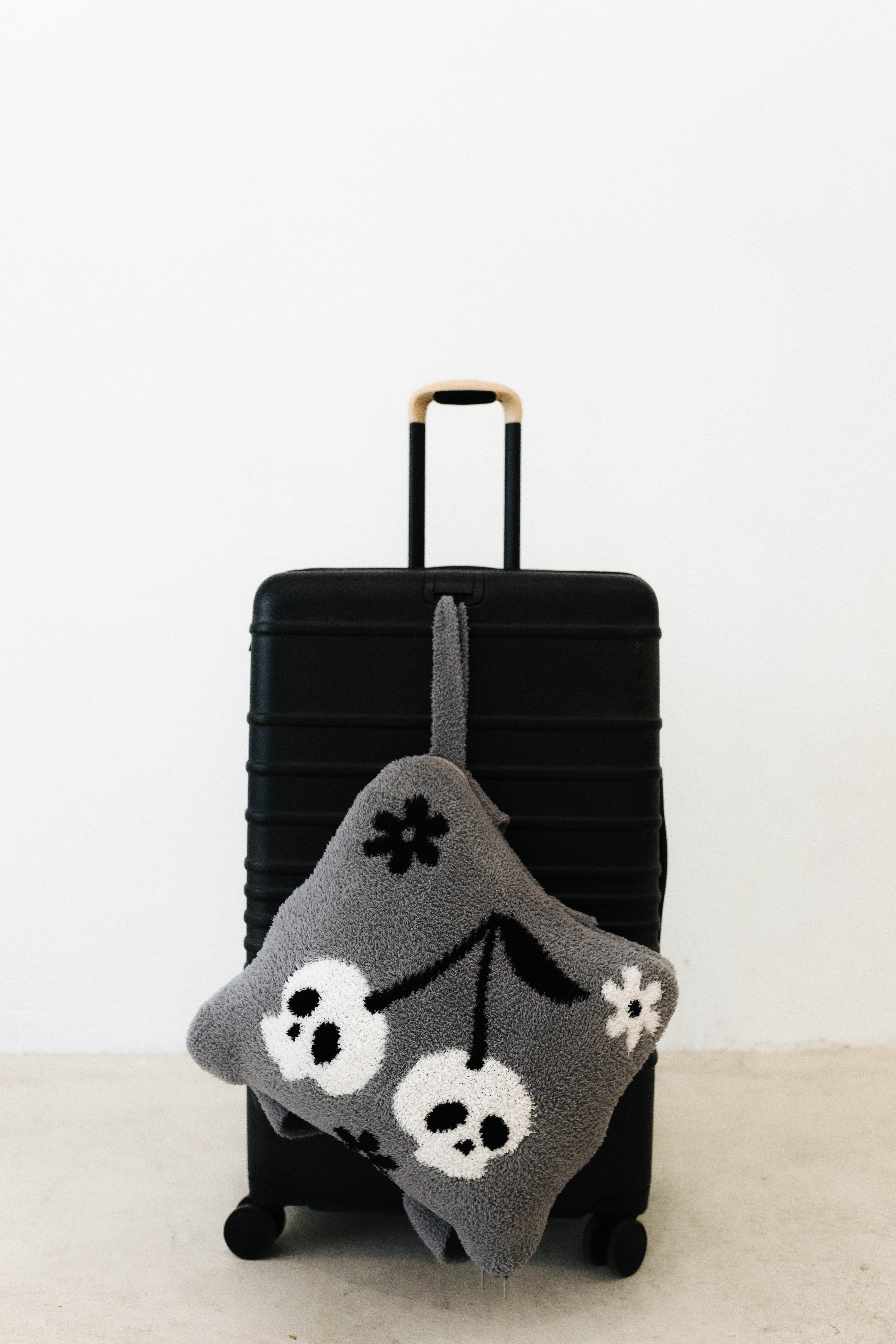 skelly backpack/wristlet quillow hanging on black suitcase