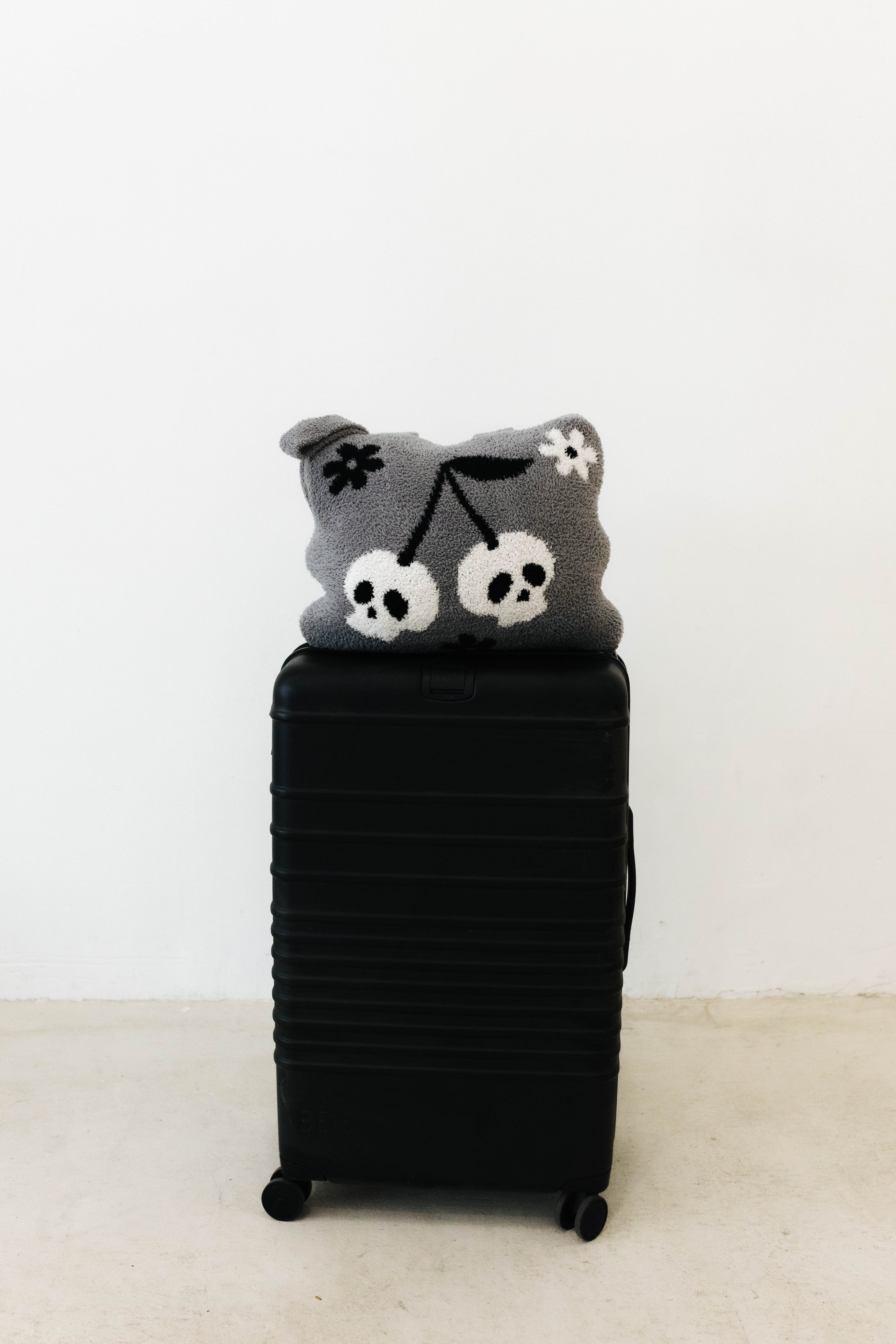 skelly backpack/wristlet quillow on top of black suitcase