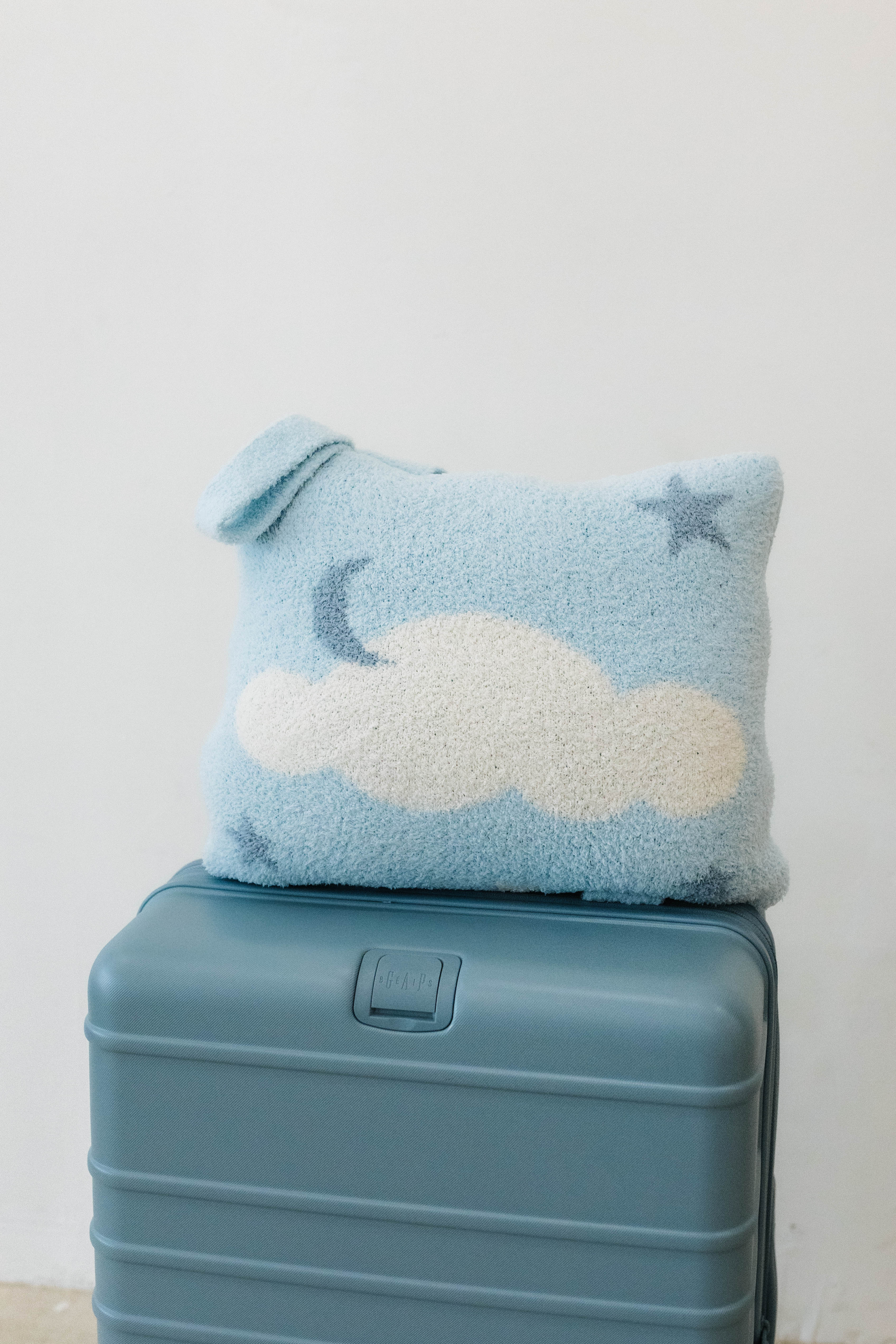 cloud backpack/wristlet quillow sitting on suitcase