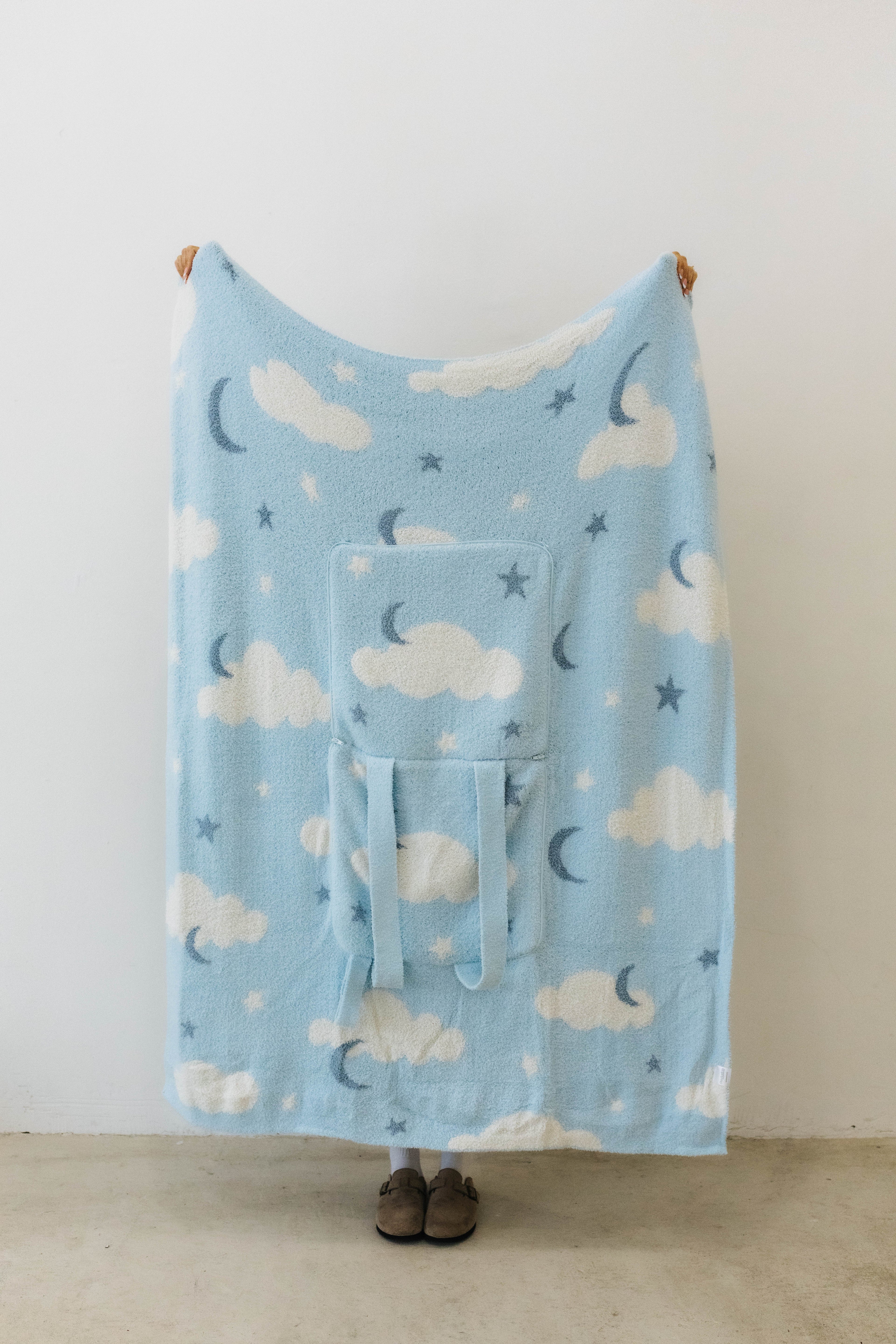cloud backpack/wristlet quillow opened showing one side of the quillow showing moon, cloud, and star print 