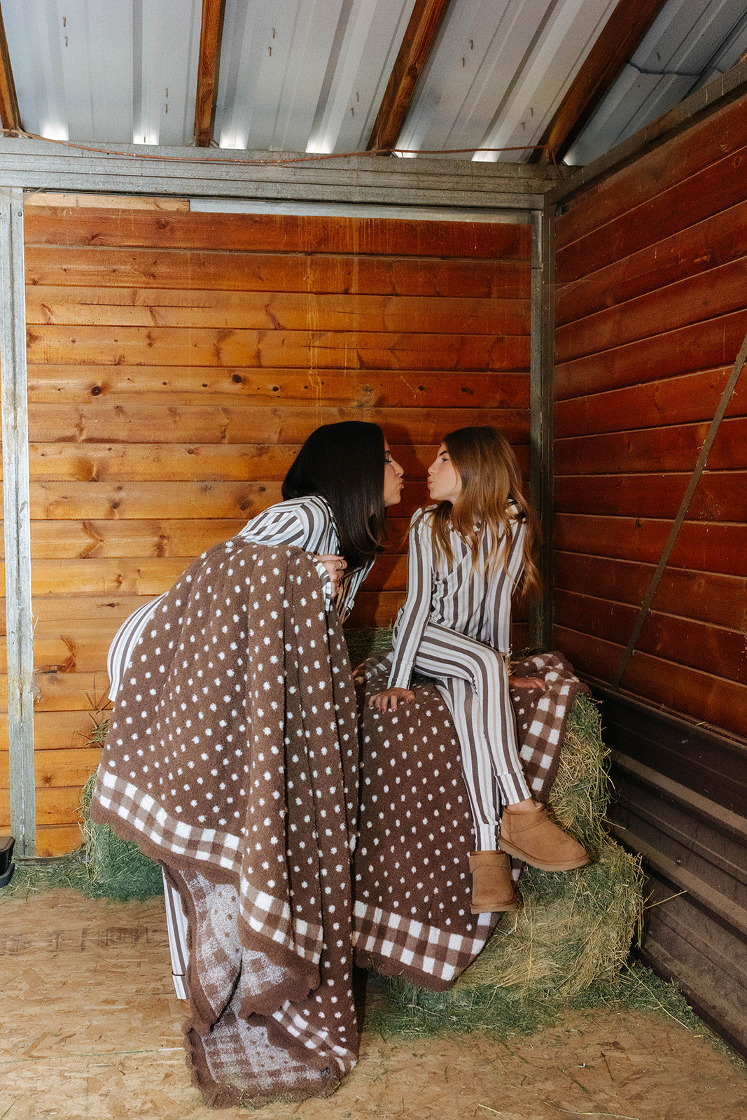 Brown gingham blanket draped over hay bales, showing the polka dot side and check border.