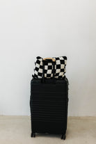 black check quillow sitting on top of the black suitcase