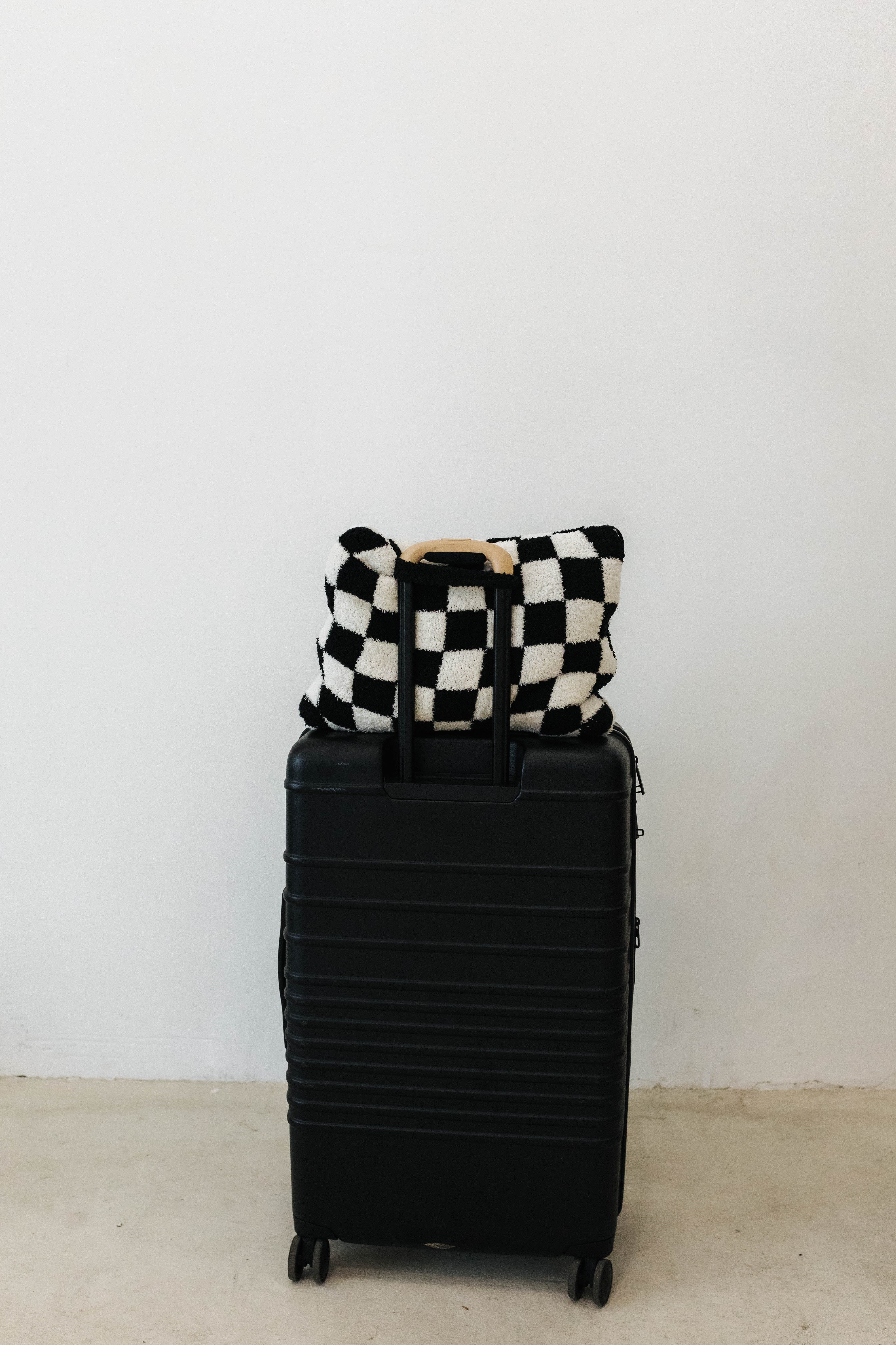 black check quillow sitting on top of the black suitcase