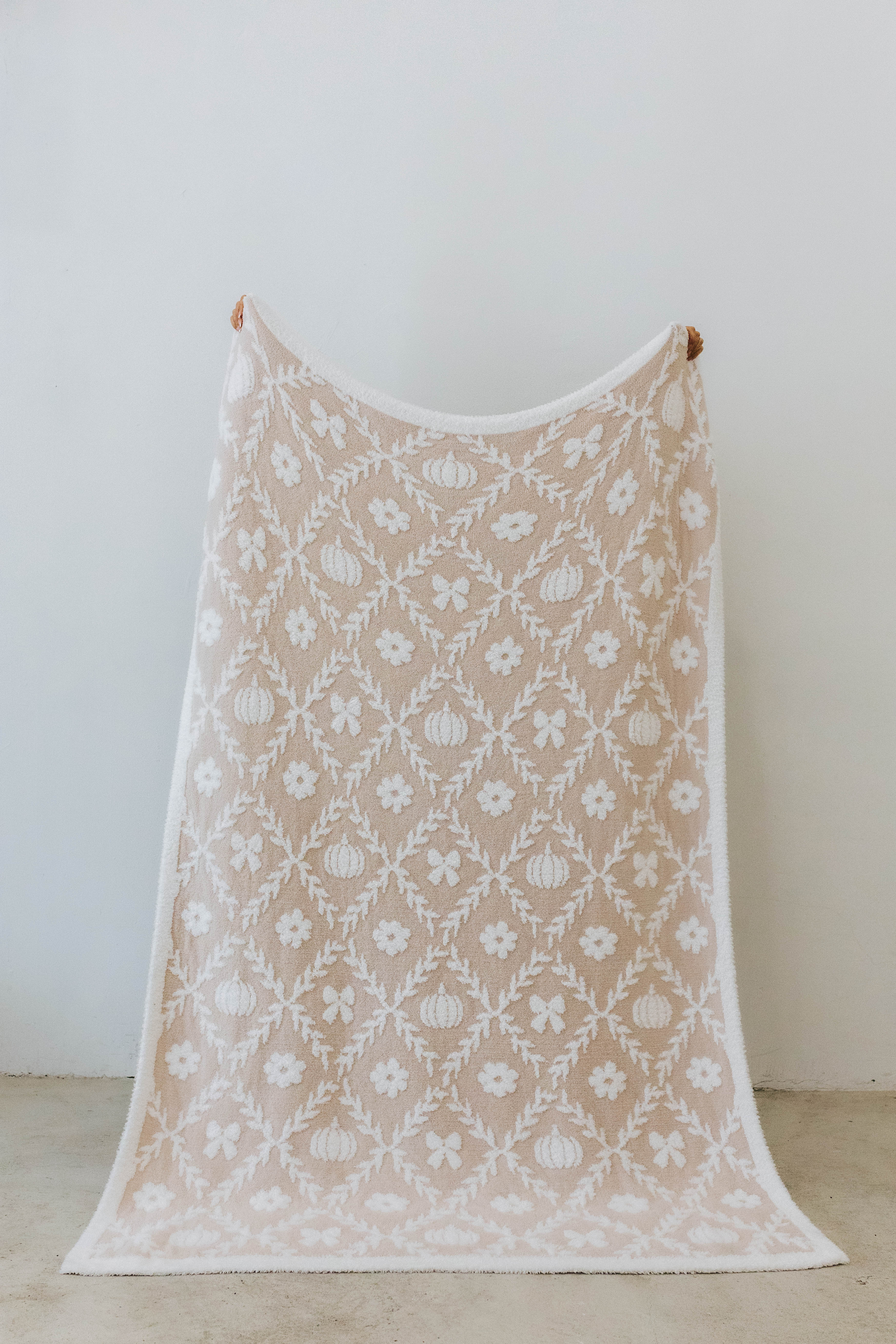 pumpkin blanket showing one side of the blanket the print has pumpkins, flowers, and bows 