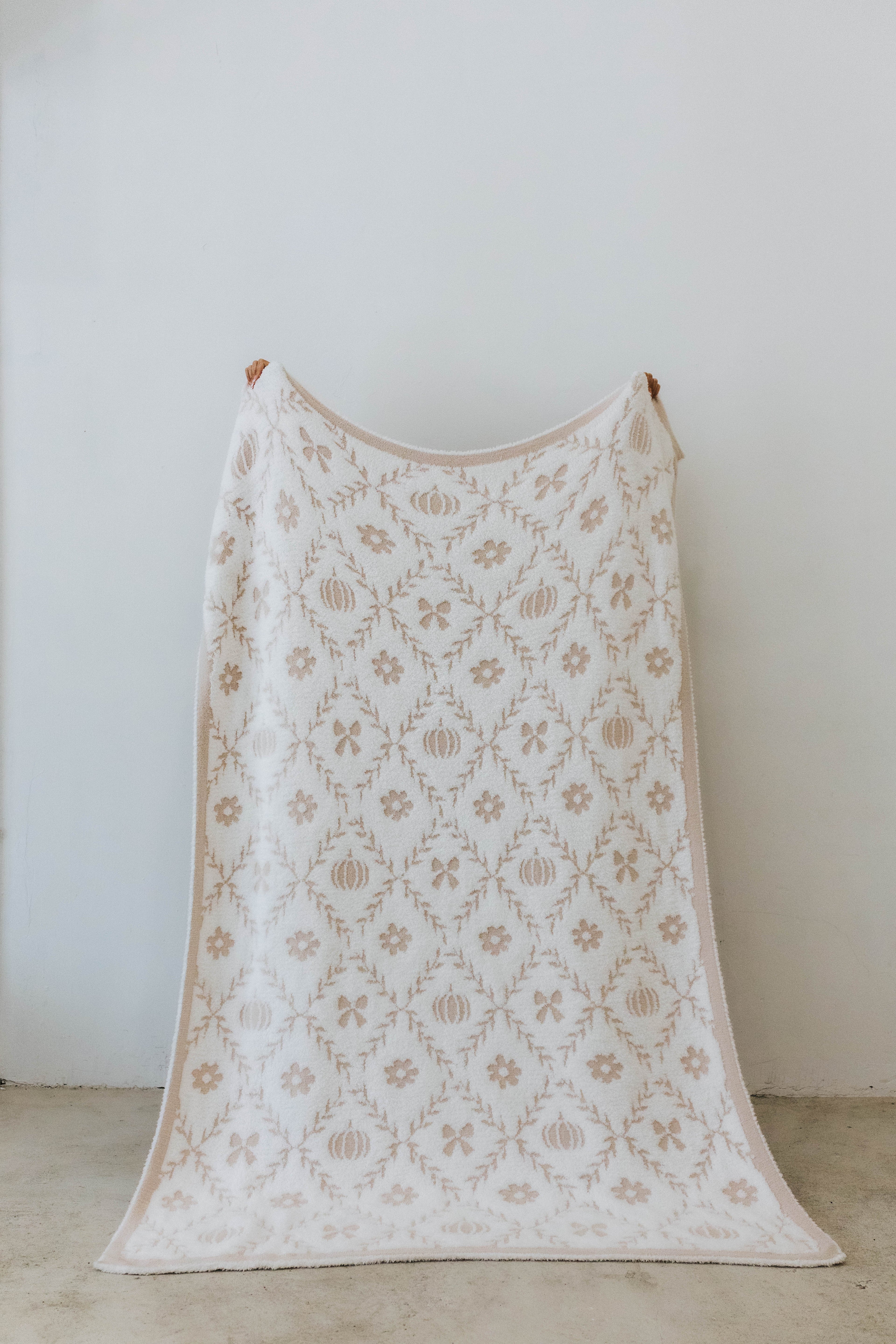 pumpkin blanket showing one side of the blanket the print has pumpkins, flowers, and bows 