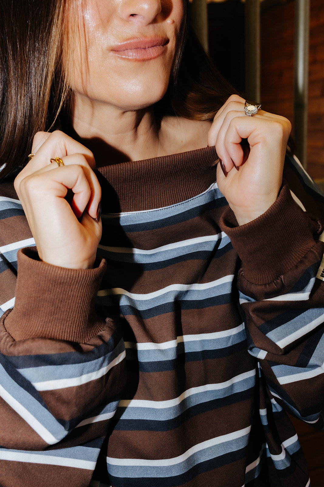 Close view of the brown ribbed neckline on the striped sweatshirt.