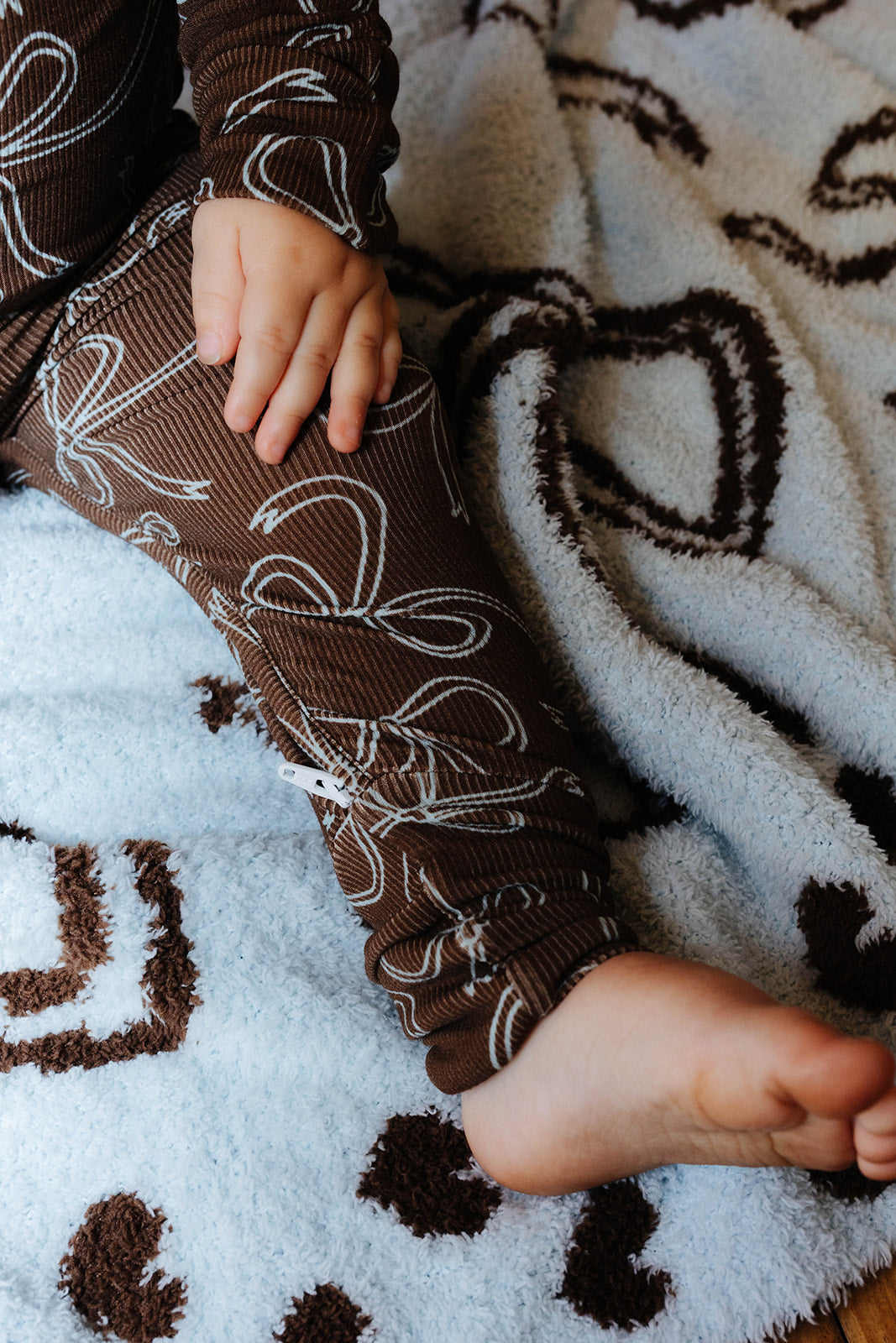 Close view of the brown bow print baby zip pajamas.
