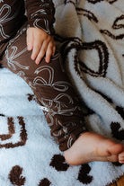Close view of the brown bow print baby zip pajamas.
