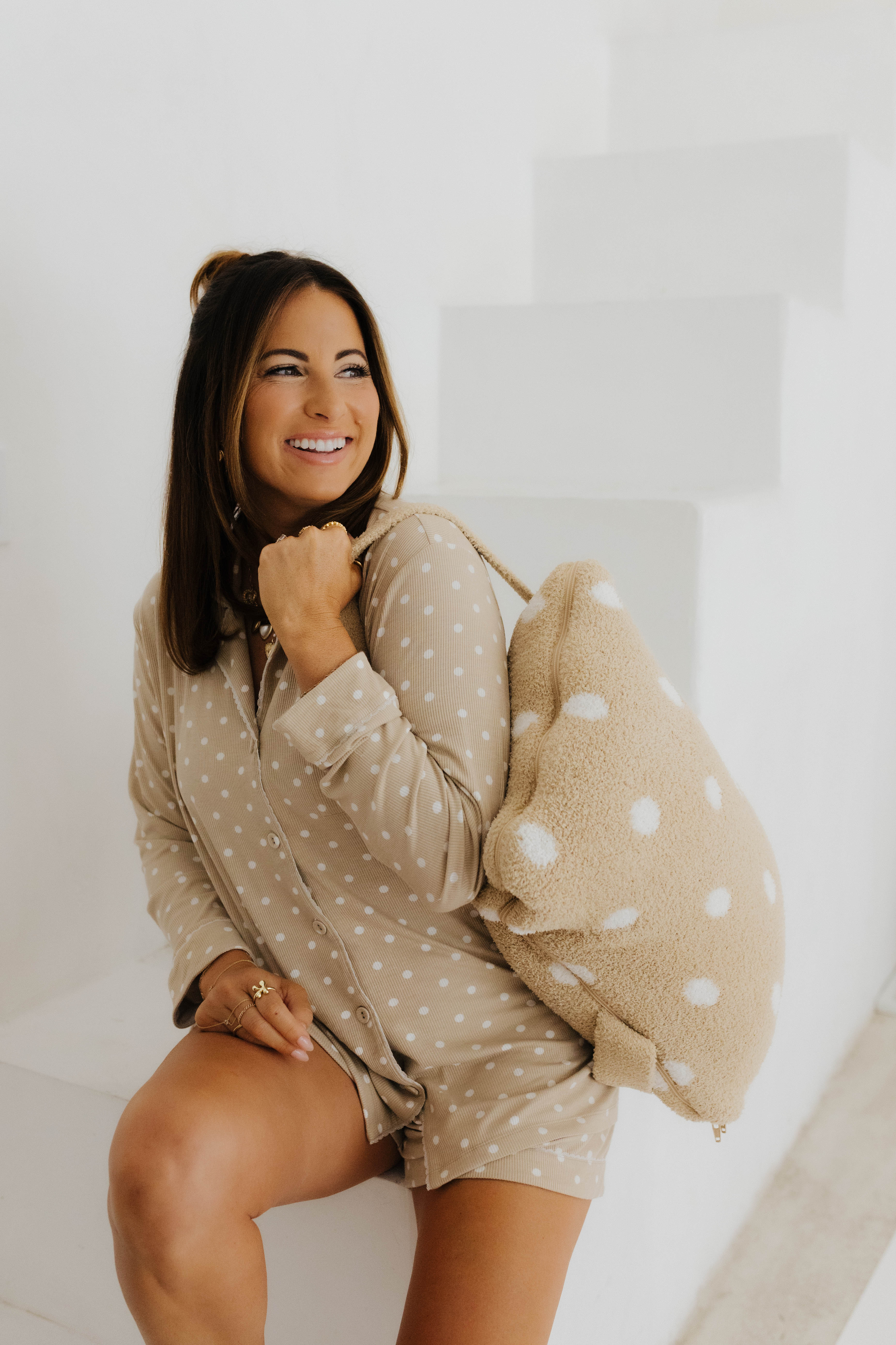 model krista smiling wearing lace polka dot pajamas and polka dot backpack quillow on shoulder 