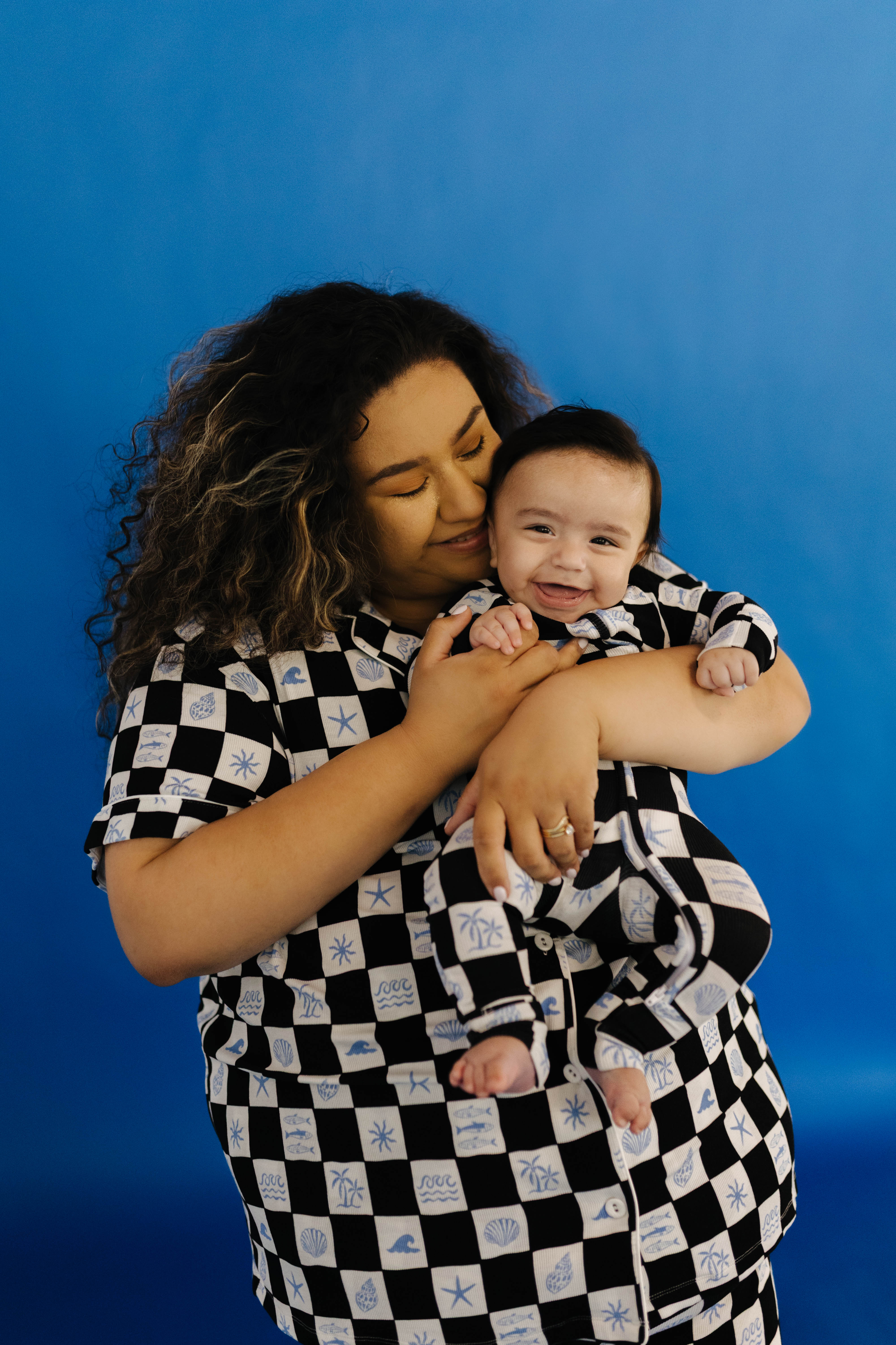 Woman and baby in matching black and white checkered pjs against a blue background