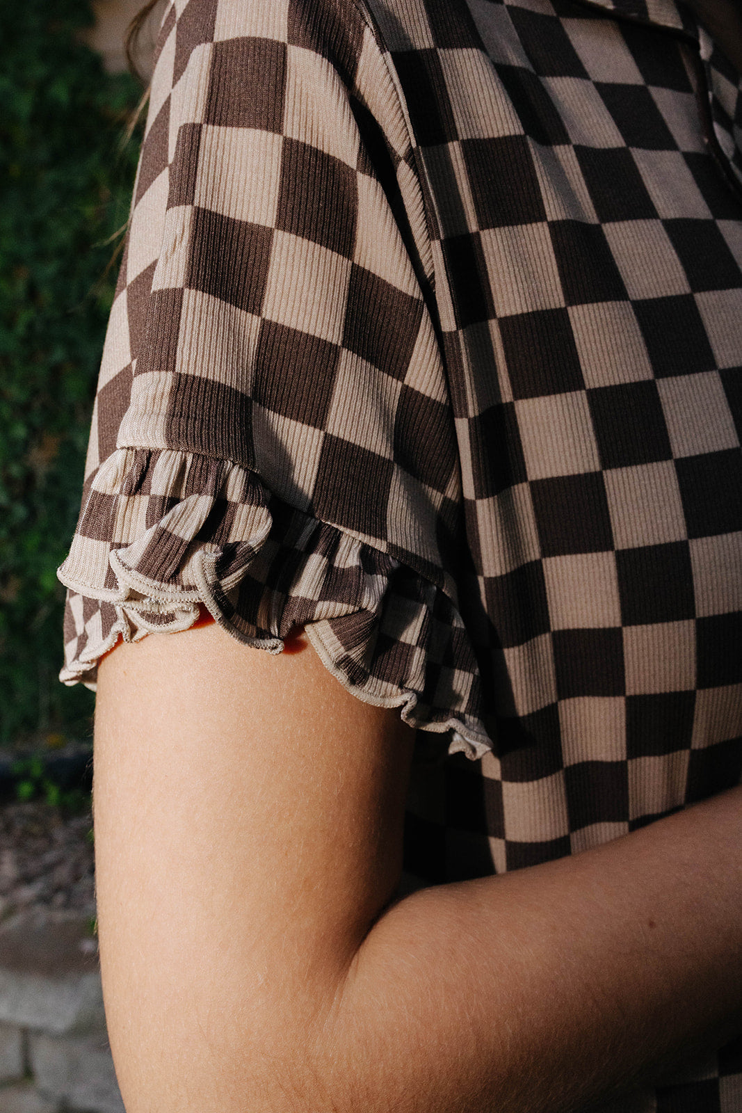 Close view of the brown check pajama shirt sleeve and scalloped edge.